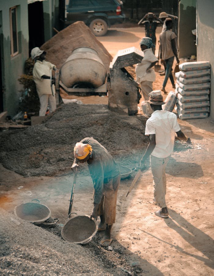 Group of construction workers engaged in labor-intensive tasks on a building site.