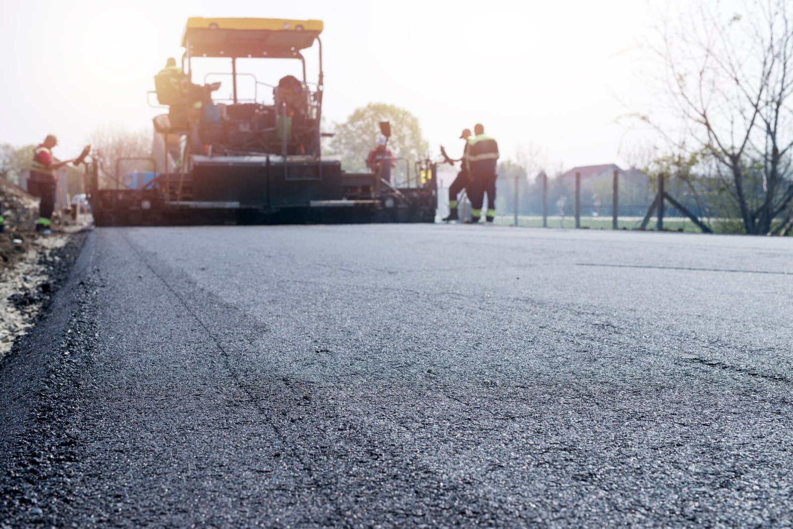 Workers placing new coating of asphalt on the road.